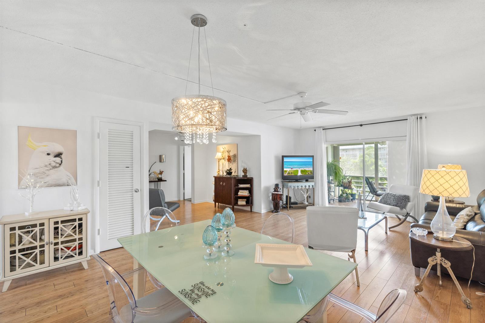 A bright dining and living area features light wood flooring, a glass table, and chandelier — 25 SE 13th Street # B3, Boca Raton FL 33432, BOCA RATON, FL