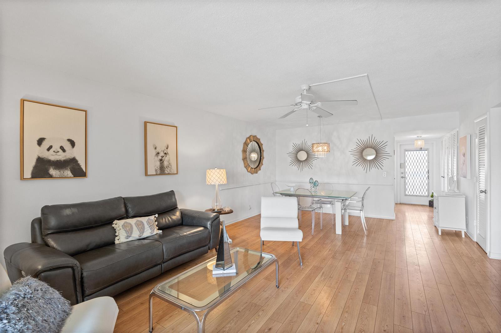 A living and dining area with a dark leather sofa, glass coffee table, and wood flooring — 25 SE 13th Street # B3, Boca Raton FL 33432, BOCA RATON, FL
