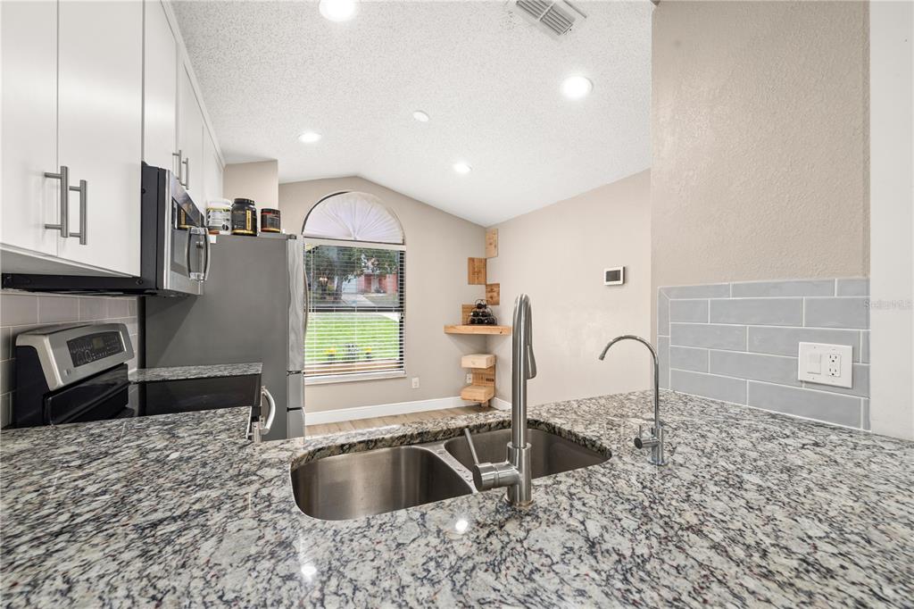 A dining area with a wooden table and chairs sits adjacent to a white kitchen — 6613 CHANTRY STREET, ORLANDO, FL