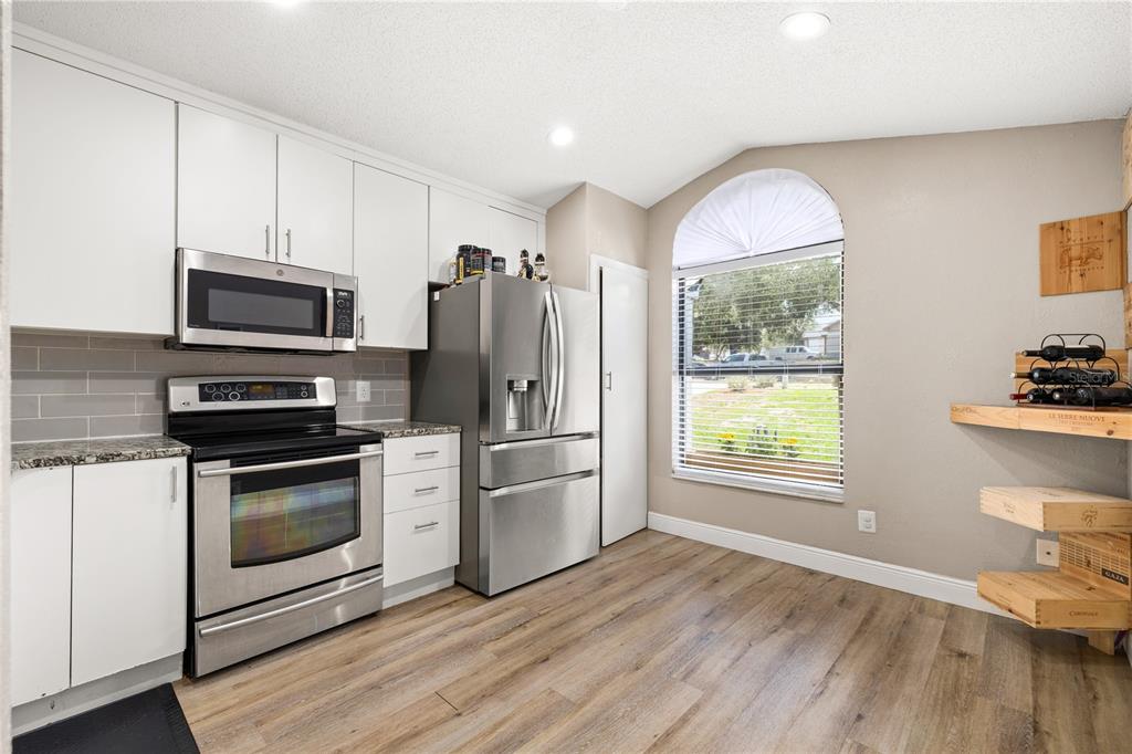 A kitchen features granite countertops, a double-basin sink, white cabinets, and a windowed breakfast nook — 6613 CHANTRY STREET, ORLANDO, FL