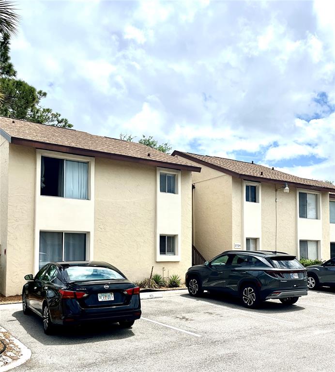 A two-story apartment building exterior with parked cars in the foreground — 2724 HIDDEN LAKE BOULEVARD UNIT A, SARASOTA, FL