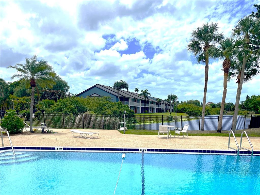 A swimming pool with depth markers sits in front of a multi-story apartment building — 2724 HIDDEN LAKE BOULEVARD UNIT A, SARASOTA, FL
