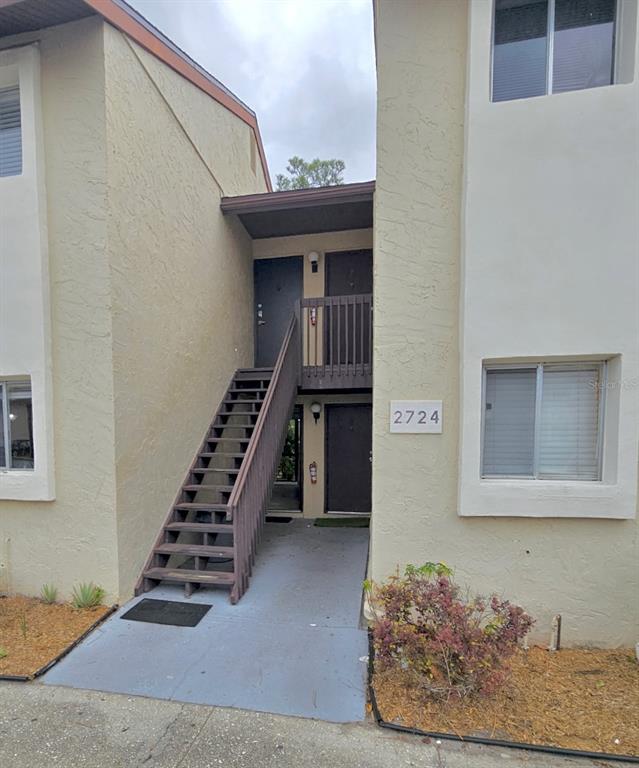 An exterior view of a two-story apartment building with a wooden staircase leading to units — 2724 HIDDEN LAKE BOULEVARD UNIT A, SARASOTA, FL