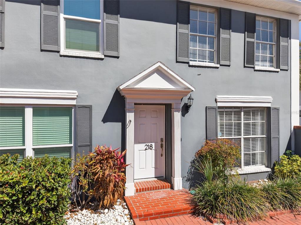 A gray two-story house exterior features a white front door with a pedimented entryway — 218 S TAMPANIA AVENUE, TAMPA, FL