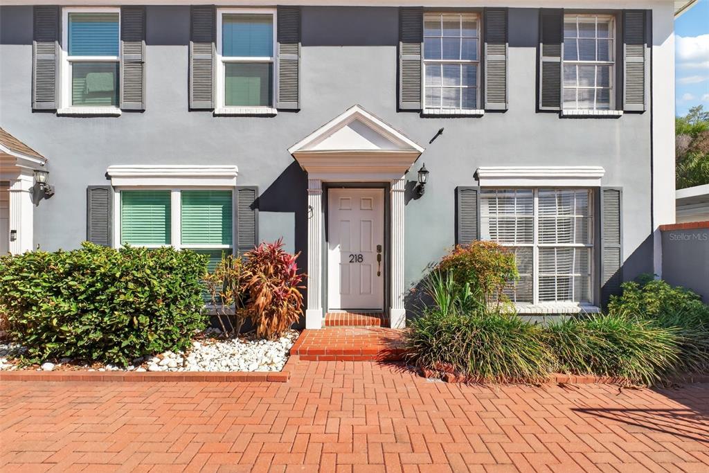 A two-story gray townhouse with a white front door and a brick walkway — 218 S TAMPANIA AVENUE, TAMPA, FL
