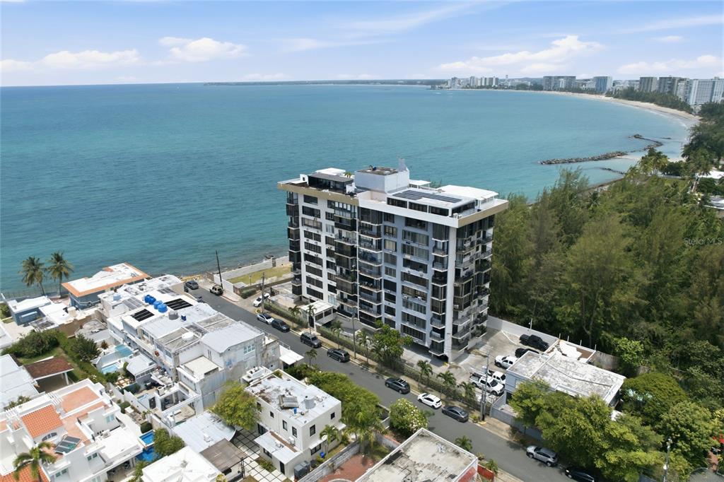 An aerial view shows a multi-story apartment building situated along a coastal shoreline — INGA 1 N COSTAMAR CONDOMINIUM UNIT PH, SAN JUAN, PR