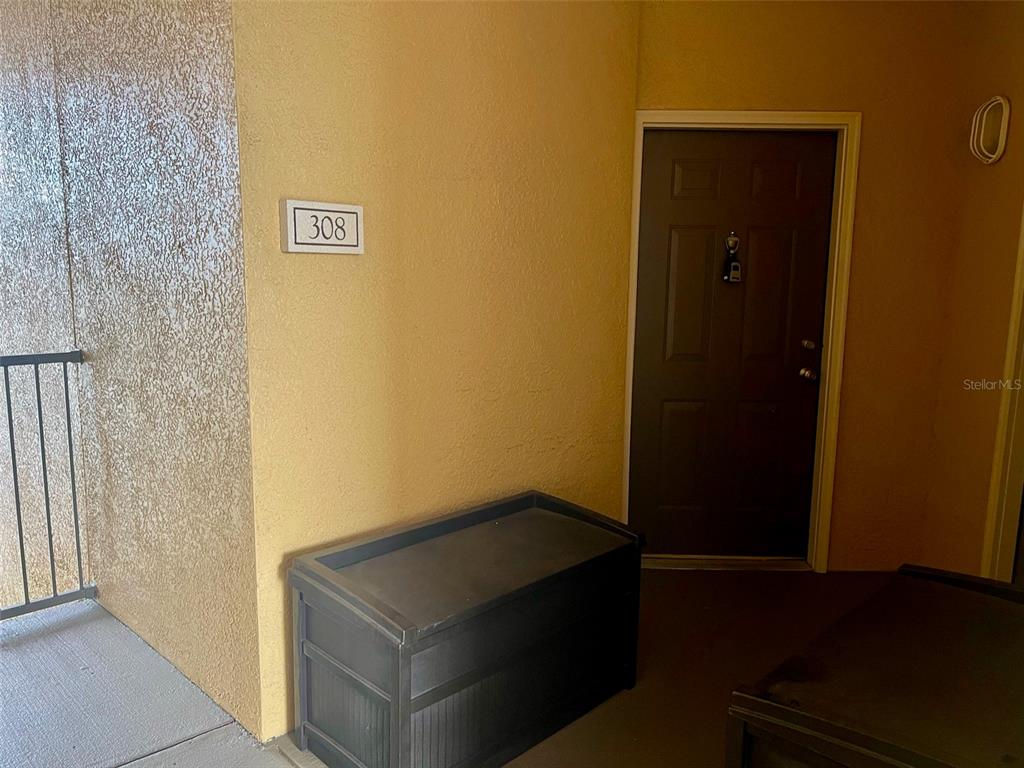 An apartment entrance with a dark door, a storage chest, and a unit number sign — 6153 METROWEST BOULEVARD UNIT 308, ORLANDO, FL