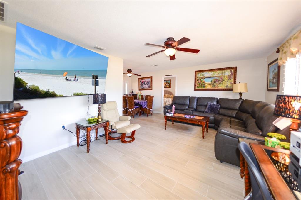 A living room with light tile flooring, a large sectional sofa, and a wall-mounted television — 190 CASA LANE, PUNTA GORDA, FL
