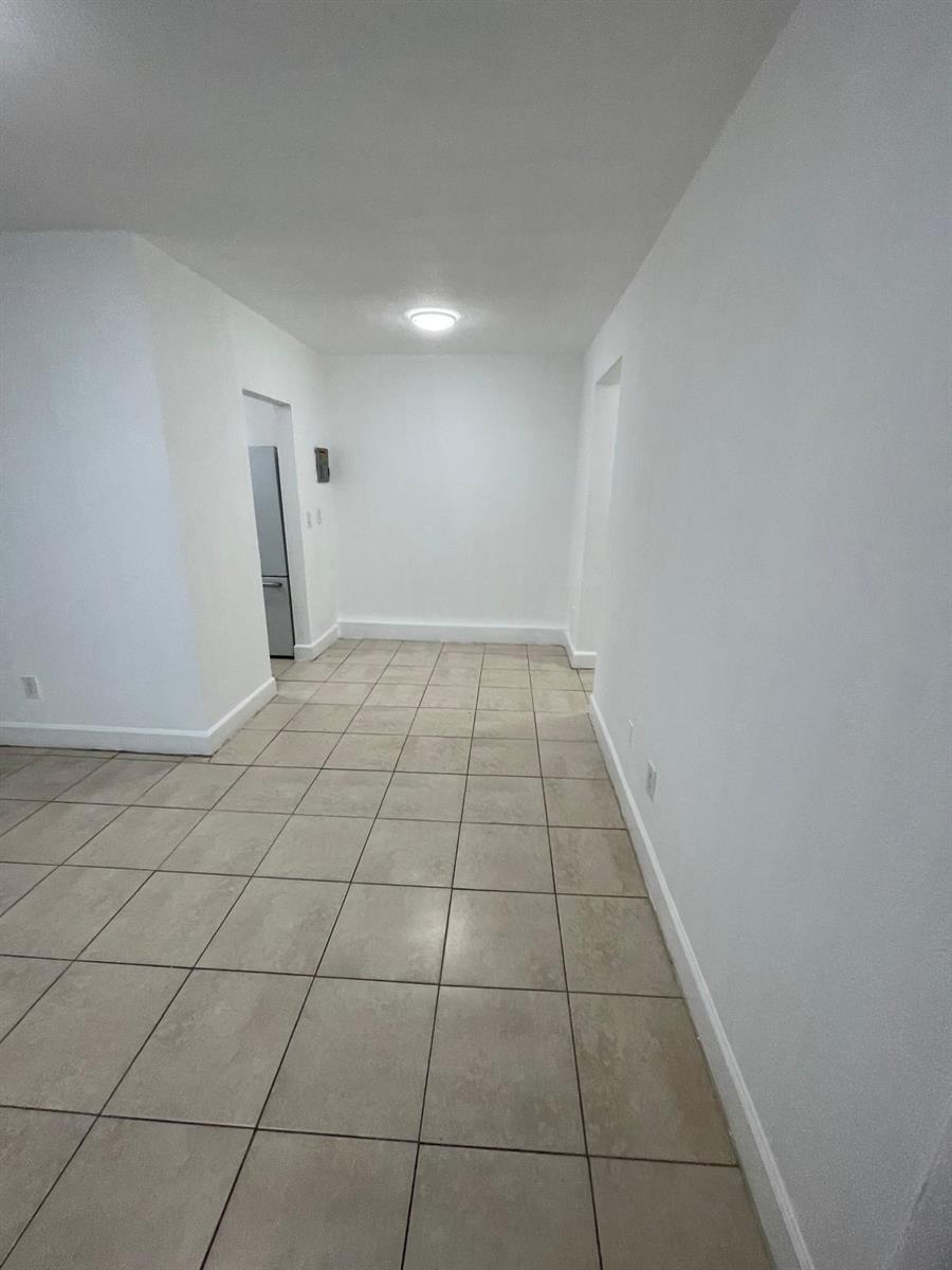 An empty room with white walls and light-colored square floor tiles — MIAMI BEACH, FL