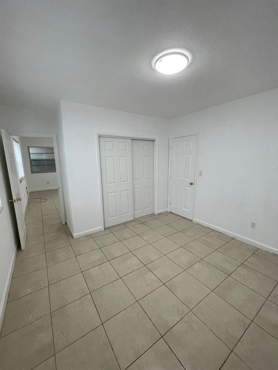 A room with white walls, tile flooring, a ceiling light, and two sets of doors — MIAMI BEACH, FL