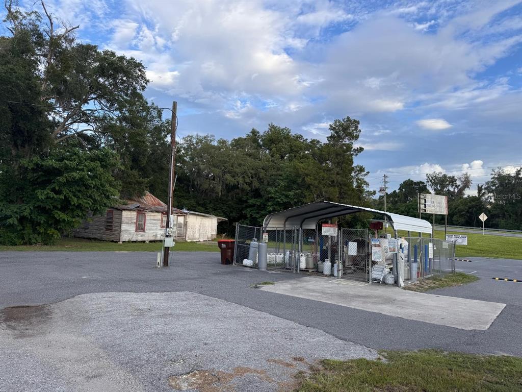 An outdoor view of a fenced propane filling station next to a weathered wooden building — 6242 SE 113TH STREET, BELLEVIEW, FL