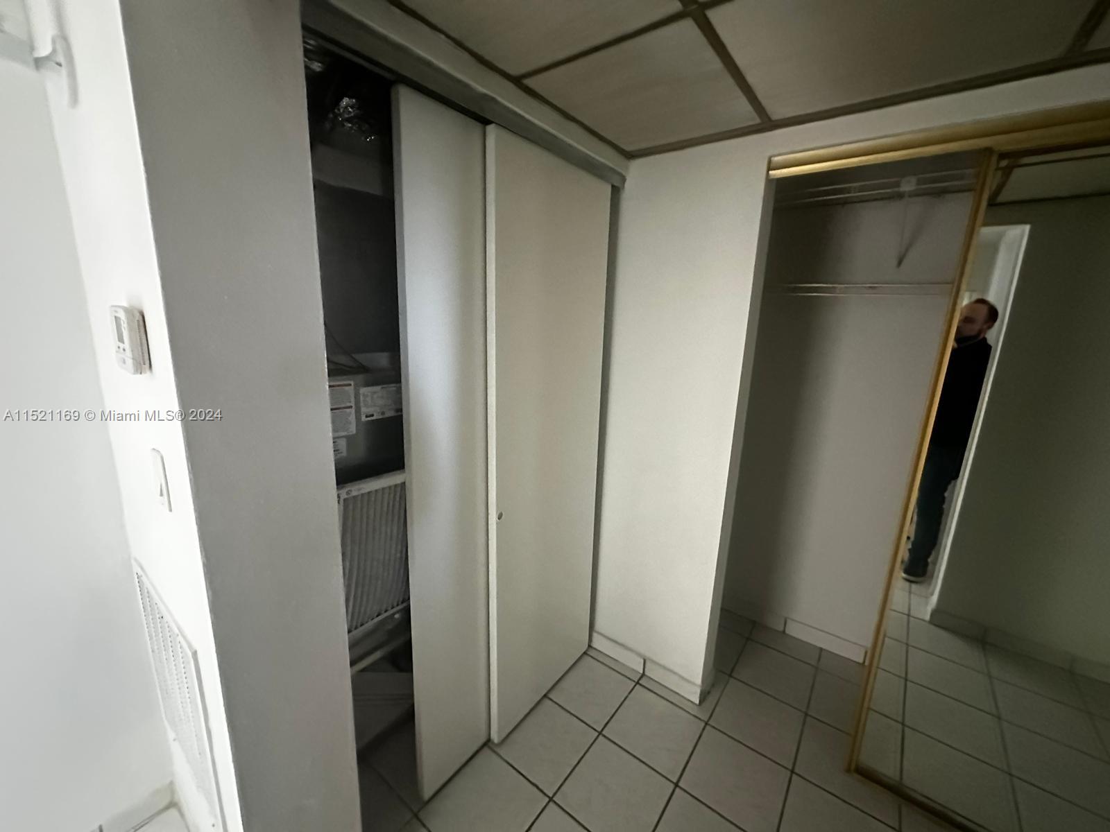 This interior view shows a tiled hallway with a utility closet and a mirrored closet — 18700 NE 3rd Ct # 626, Miami FL 33179, MIAMI, FL