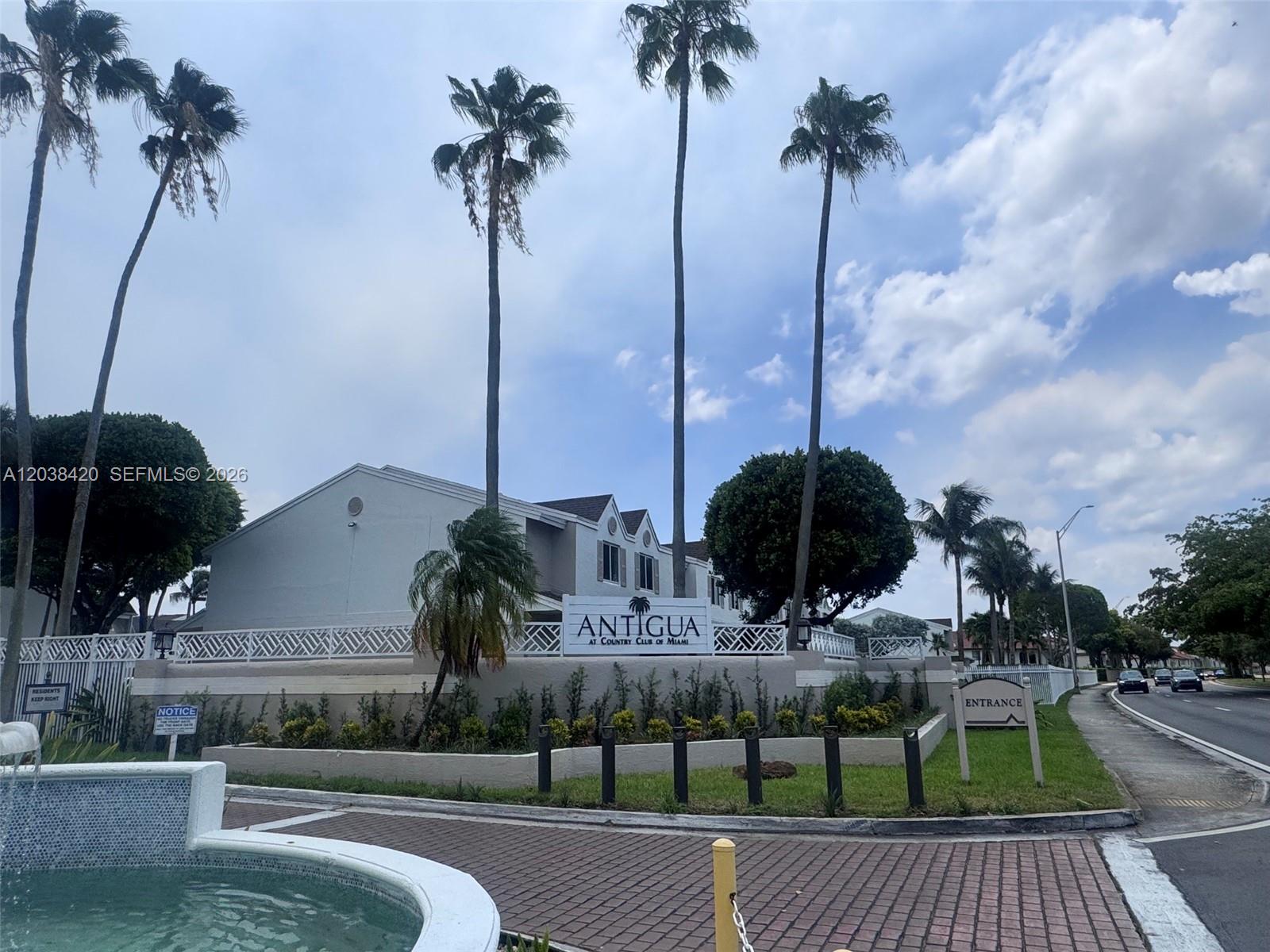 The exterior of a residential complex features a sign for Antigua at Country Club of Miami — 17425 NW 67th Pl # 13, Hialeah FL 33015, HIALEAH, FL