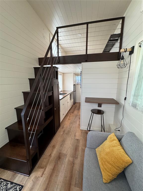 A tiny house interior features a wooden staircase with storage, a loft, and a kitchenette — NW 4TH STREET, OCALA, FL