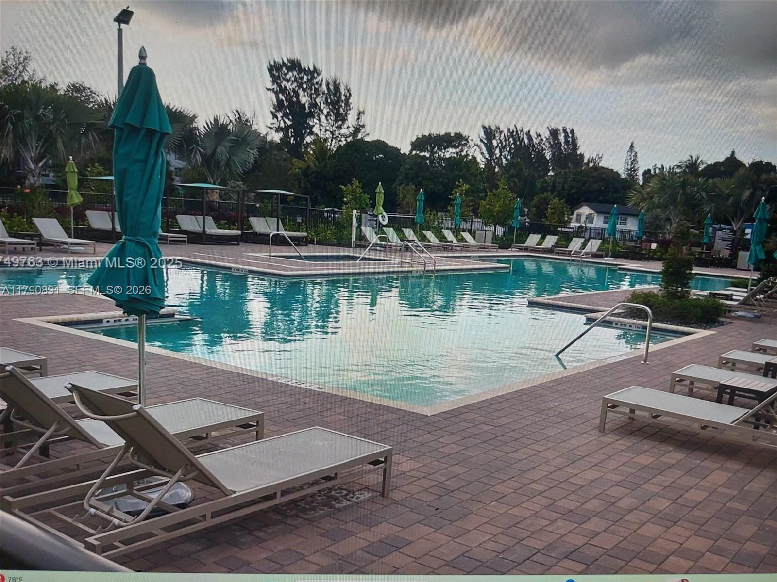 A swimming pool with lounge chairs and umbrellas on a brick patio — 12234 NW 23rd Path, Miami FL 33167, MIAMI, FL