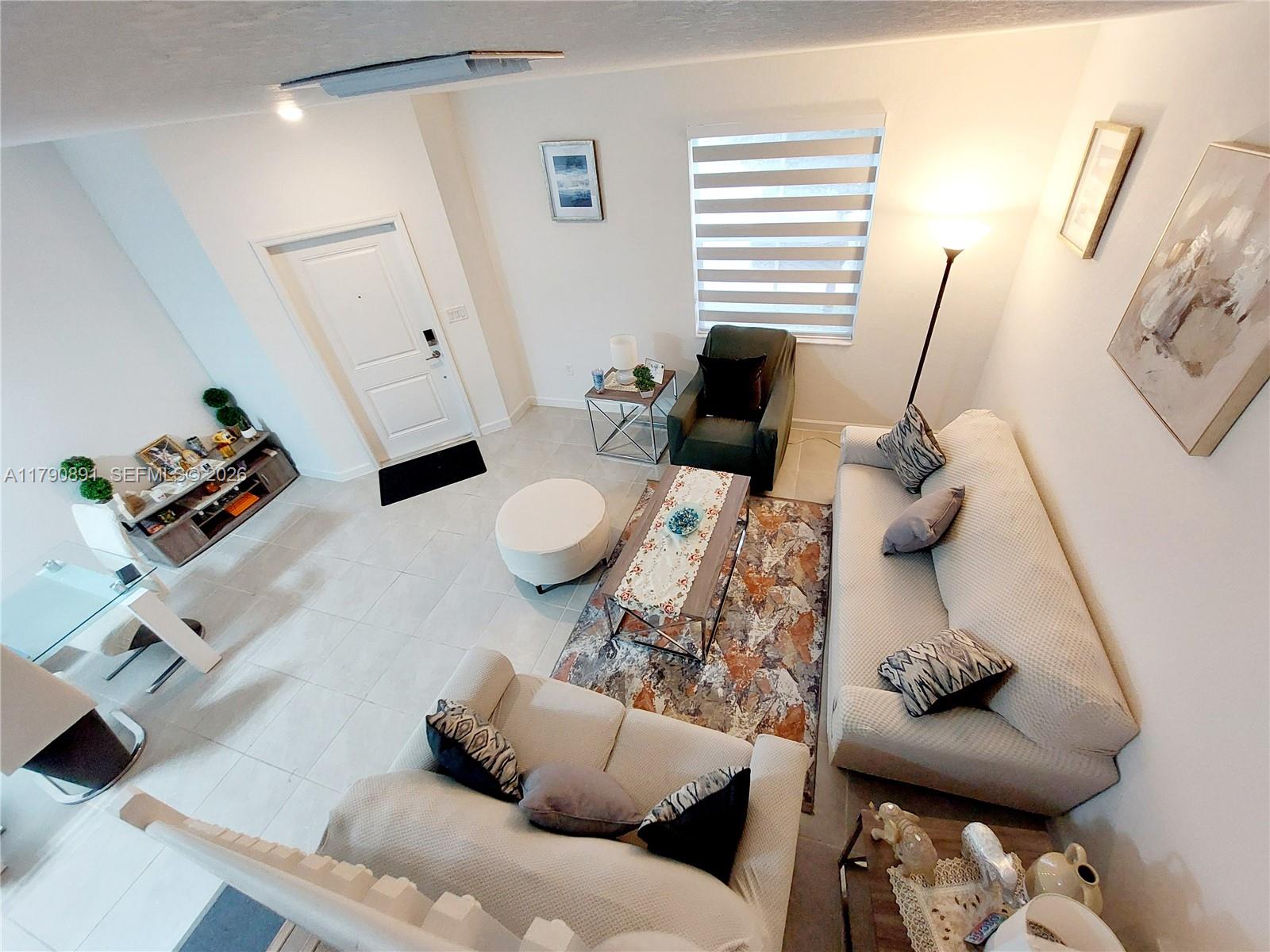 An elevated view of a living room featuring tiled floors, a sofa, and an armchair — 12234 NW 23rd Path, Miami FL 33167, MIAMI, FL
