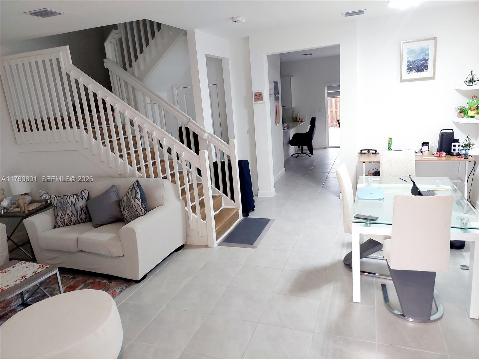 A living room with a staircase, white tile floors, and an adjacent dining area — 12234 NW 23rd Path, Miami FL 33167, MIAMI, FL