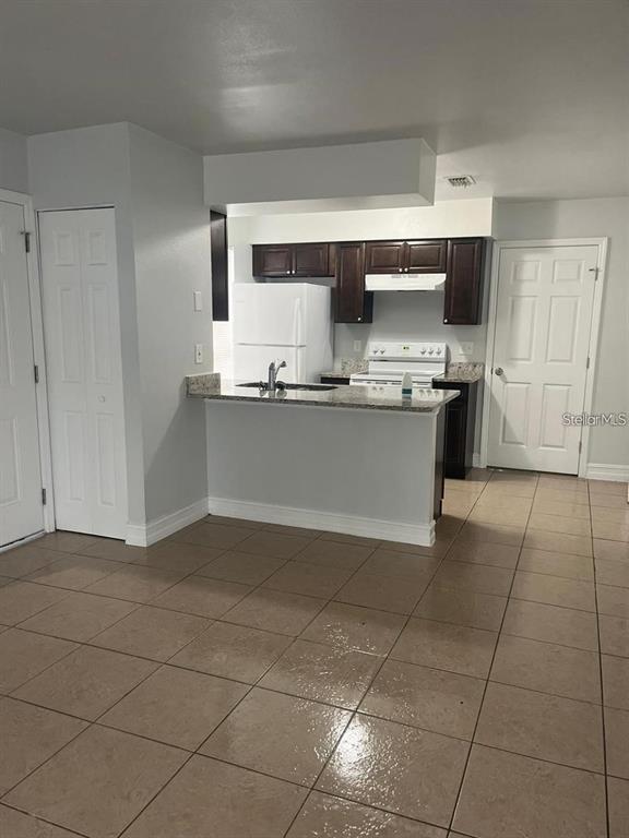 A kitchen with dark cabinets, white appliances, and a granite-topped breakfast bar — 1805 CRYSTAL GROVE DRIVE UNIT 1805, LAKELAND, FL