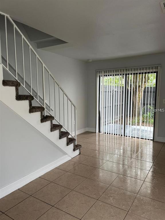 A room with tile flooring, a staircase with brown carpeted steps, and sliding glass doors — 1805 CRYSTAL GROVE DRIVE UNIT 1805, LAKELAND, FL