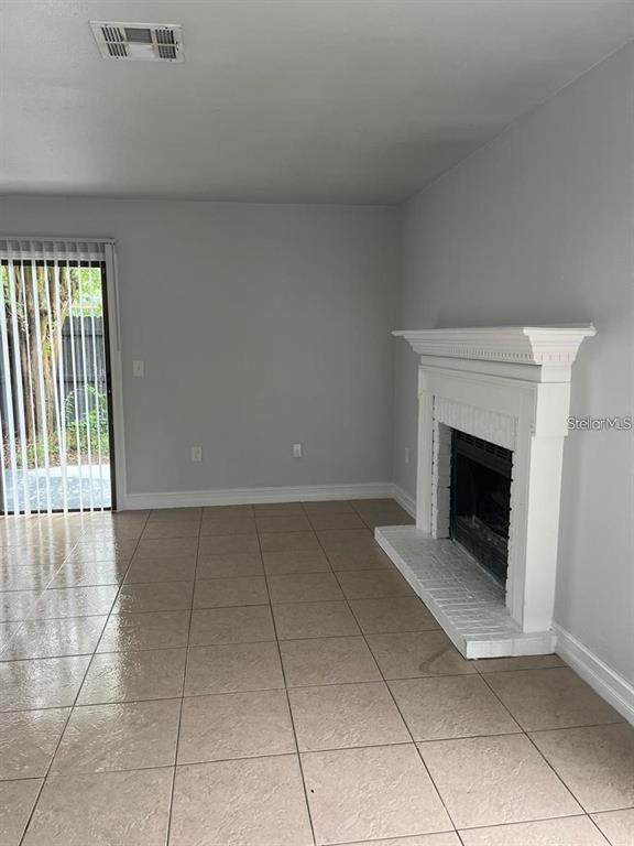 A living room features light-colored tile flooring, a white fireplace, and a sliding glass door — 1805 CRYSTAL GROVE DRIVE UNIT 1805, LAKELAND, FL