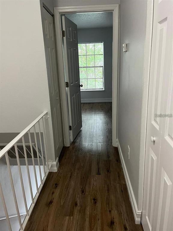 A hallway with wood-look flooring leads to a bedroom with a window — 1805 CRYSTAL GROVE DRIVE UNIT 1805, LAKELAND, FL