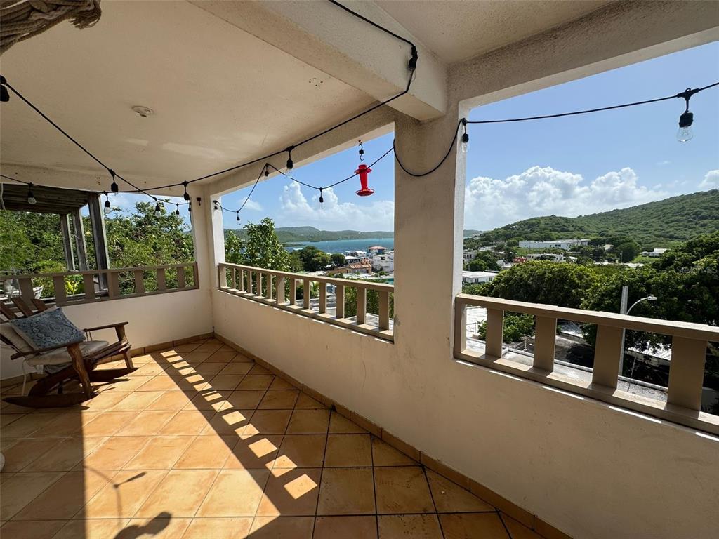 A covered balcony features tiled flooring, a wooden rocking chair, and views of the ocean — 27 WILLIAM FONT STREET, CULEBRA, PR