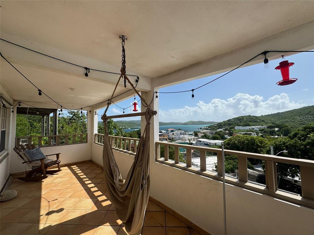A covered balcony features a hammock, a rocking chair, and a scenic coastal view — 27 WILLIAM FONT STREET, CULEBRA, PR