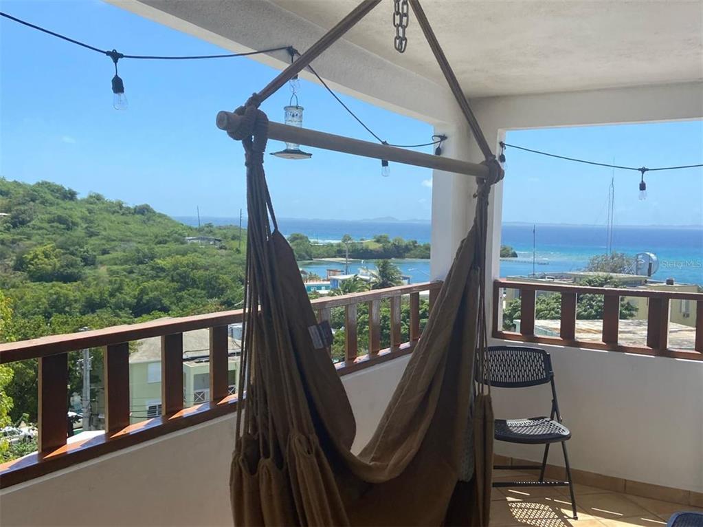 A balcony features a hanging chair, string lights, and a view of the ocean — 27 WILLIAM FONT STREET, CULEBRA, PR