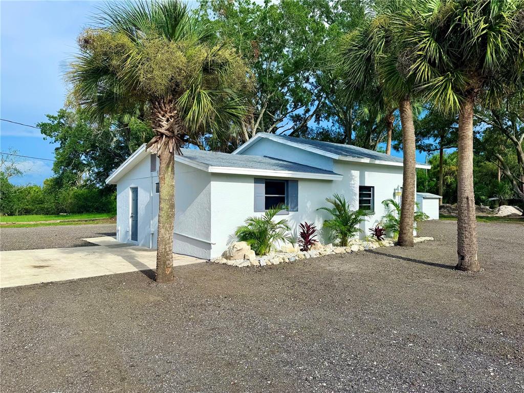 A white, single-story house with a gravel yard and palm trees under a blue sky — 1322 N PINELLAS AVENUE, TARPON SPRINGS, FL