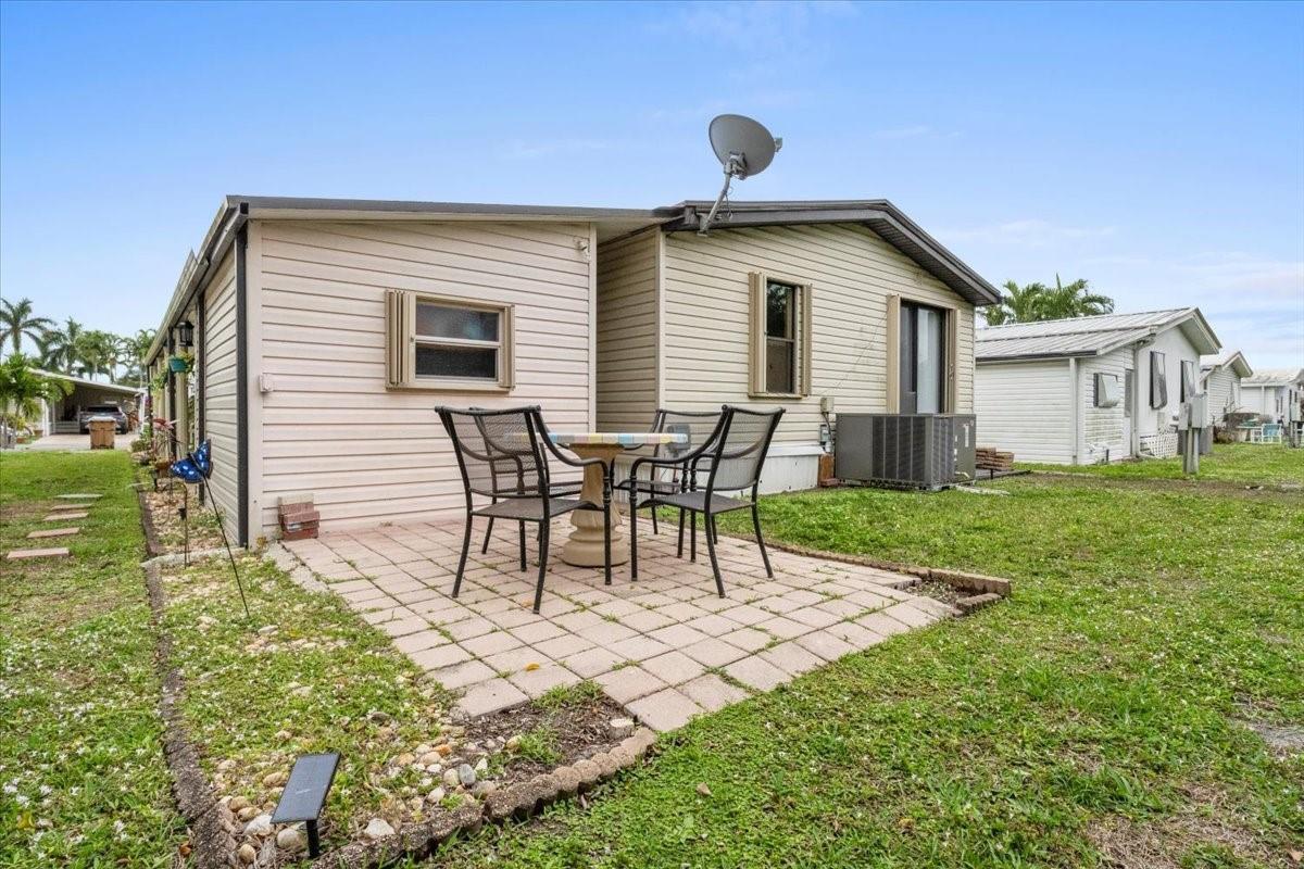 A beige mobile home features a paved patio with a table and chairs in the yard — 5343 NW 4th Terrace, Deerfield Beach FL 33064, DEERFIELD BEACH, FL