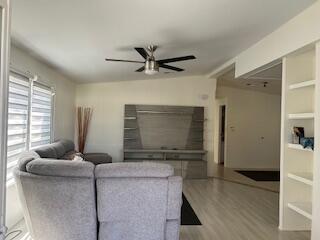 A living room features a grey sectional sofa, a modern entertainment center, and light wood flooring — 5343 NW 4th Terrace, Deerfield Beach FL 33064, DEERFIELD BEACH, FL