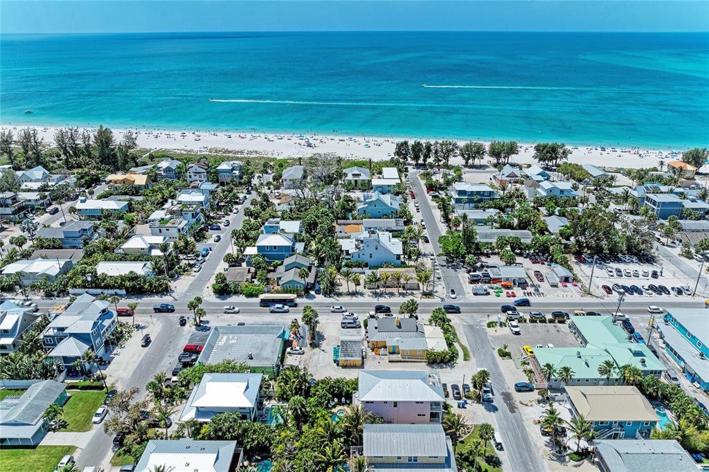 An aerial view shows a coastal neighborhood with houses, streets, and a sandy beach — 101 PALM AVENUE UNIT 4, ANNA MARIA, FL