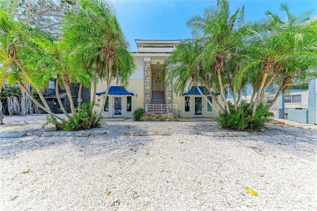 A two-story building with a shell-covered parking area and palm trees in the front — 101 PALM AVENUE UNIT 4, ANNA MARIA, FL