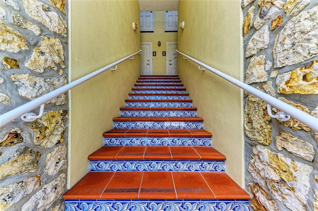 An outdoor staircase with decorative blue and white tile risers leads to two white doors — 101 PALM AVENUE UNIT 4, ANNA MARIA, FL