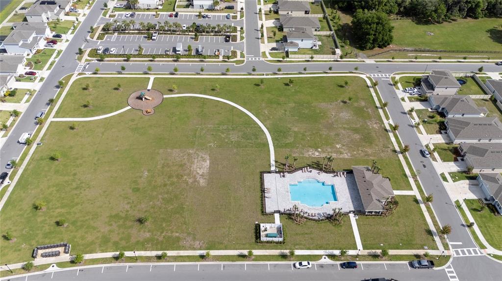 An aerial view shows a community park with a swimming pool, playground, and surrounding houses — 1491 AUGUST GRAY DRIVE, KISSIMMEE, FL