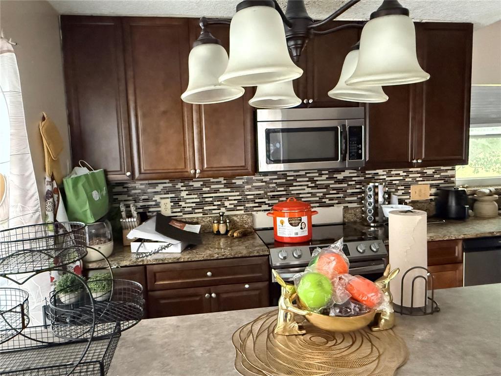 A kitchen features dark wood cabinets, a stainless steel microwave, and a tiled backsplash — 2665 STALEY COURT, ORLANDO, FL