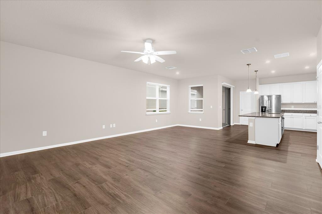 An open-concept living room with wood-look flooring flows into a kitchen with white cabinets — 6162 GLORY BOWER DRIVE, WINTER GARDEN, FL