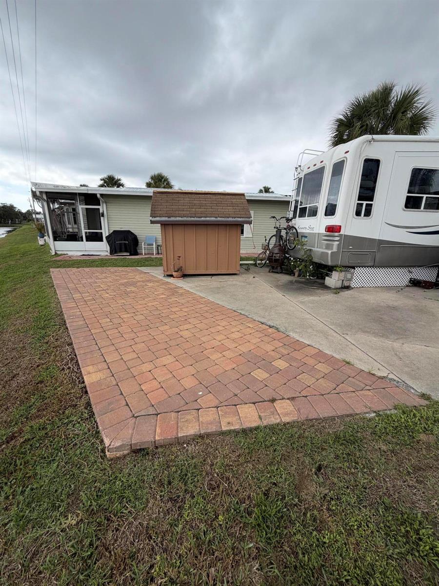 A paved patio area sits between a small wooden shed and a parked recreational vehicle — 5240 SE 67th Avenue SE, Okeechobee FL 34974, OKEECHOBEE, FL
