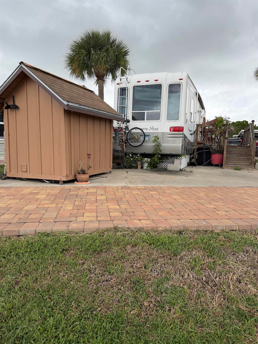 A brown wooden shed stands next to a parked recreational vehicle on a concrete pad — 5240 SE 67th Avenue SE, Okeechobee FL 34974, OKEECHOBEE, FL