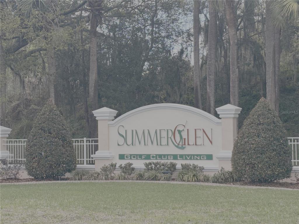 A stone entrance sign for SummerGlen Golf Club Living stands before a wooded area — 15596 SW 13TH CIRCLE, OCALA, FL