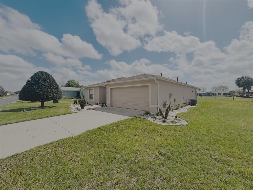 A single-story house with a beige exterior, a two-car garage, and a landscaped front yard — 15596 SW 13TH CIRCLE, OCALA, FL