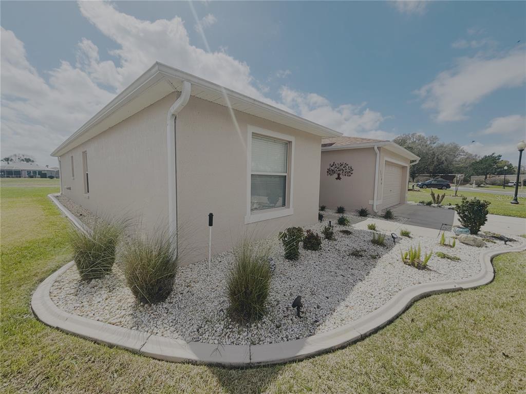 A single-story house with beige stucco siding, a white rock garden, and a concrete driveway — 15596 SW 13TH CIRCLE, OCALA, FL