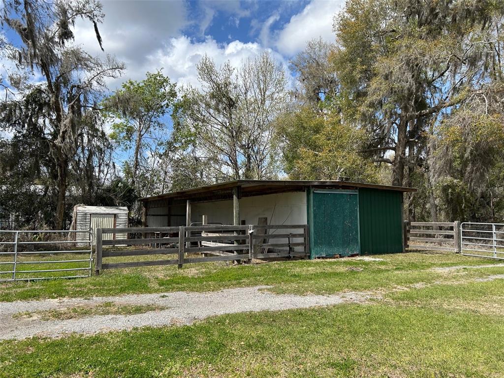 A wooden barn with a green sliding door stands behind a fenced pasture with trees — 13925 NW US-441, ALACHUA, FL