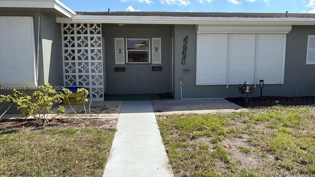 The exterior of a single-story house features a concrete walkway, decorative breeze blocks, and shutters — 775 North Dr # A, Delray Beach FL 33445, DELRAY BEACH, FL