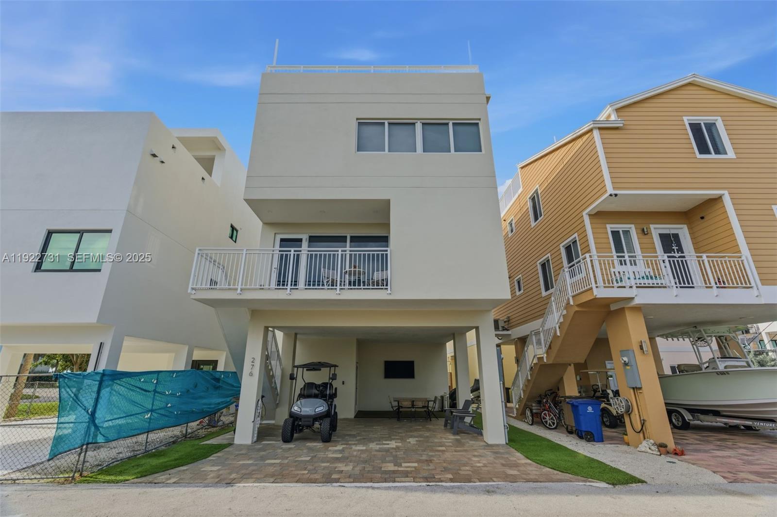 A modern three-story house with a ground-level garage, balcony, and a golf cart parked underneath — 94825 Overseas hwy 276, Key Largo FL 33037, KEY LARGO, FL