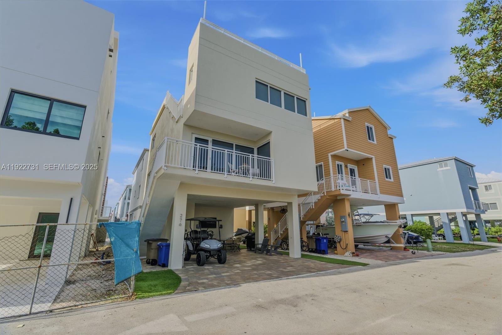 An elevated house with a golf cart parked in the ground-level carport area — 94825 Overseas hwy 276, Key Largo FL 33037, KEY LARGO, FL
