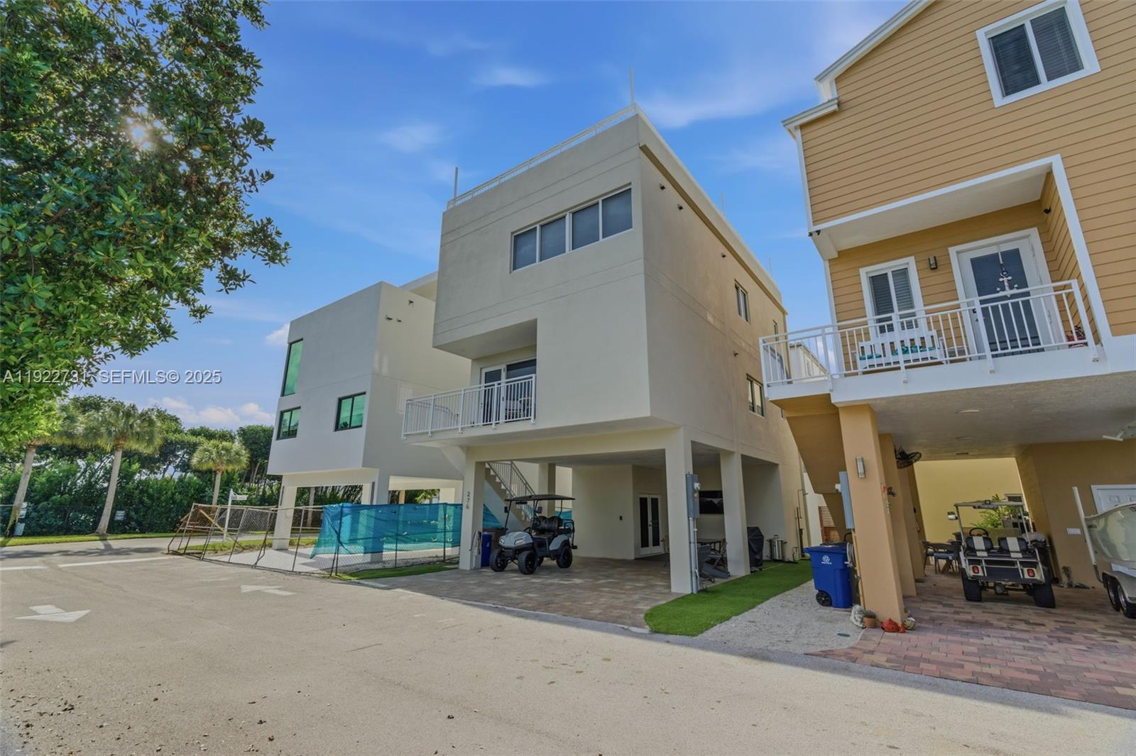 An exterior view shows two modern elevated houses with ground-level parking and golf carts — 94825 Overseas hwy 276, Key Largo FL 33037, KEY LARGO, FL