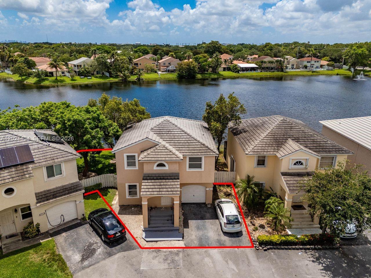 An aerial view shows a two-story house with a driveway and lakefront backyard — 850 NW 98th Ave, Plantation FL 33324, PLANTATION, FL