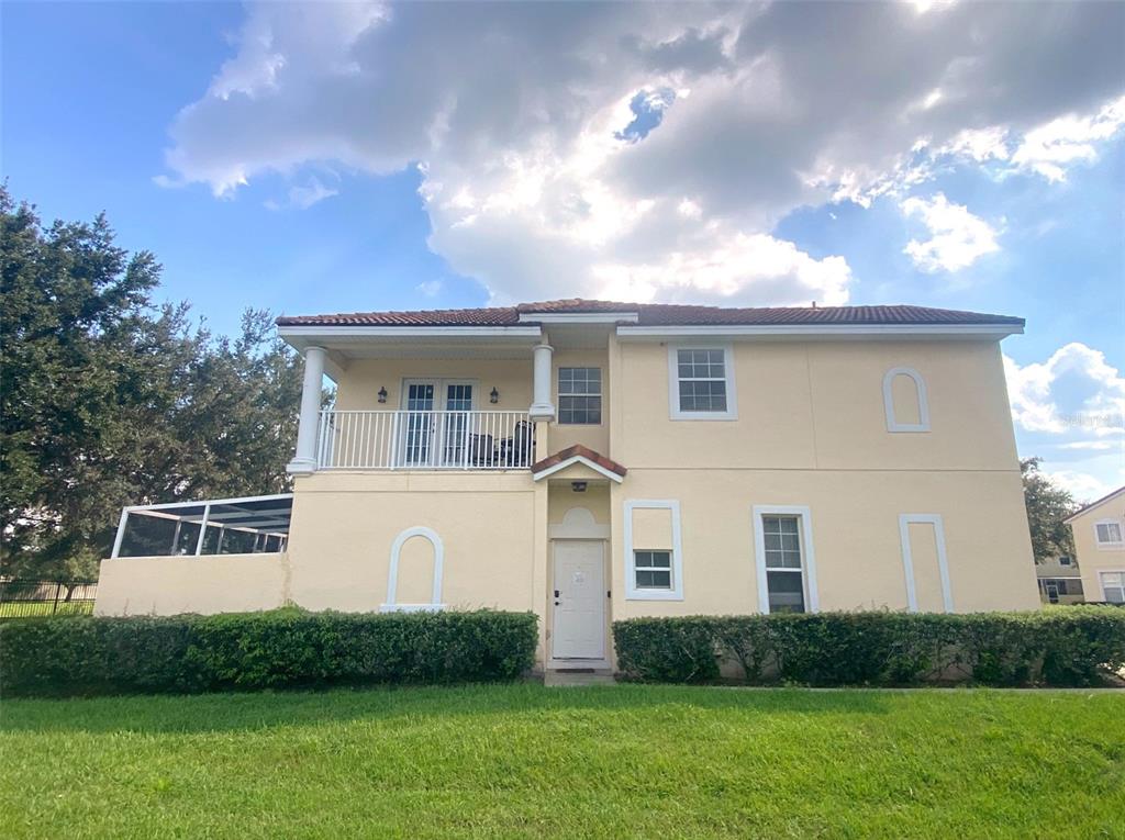 A two-story, light yellow stucco house features a second-floor balcony and a front entrance — 1282 S BEACH CIRCLE, KISSIMMEE, FL