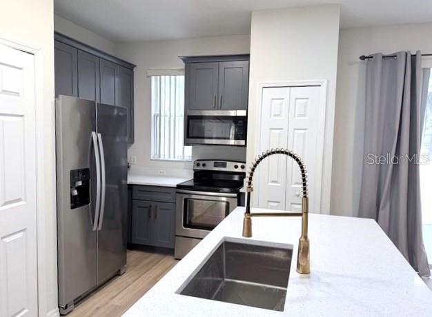 A modern kitchen features gray cabinets, stainless steel appliances, and a white quartz island countertop — 1282 S BEACH CIRCLE, KISSIMMEE, FL